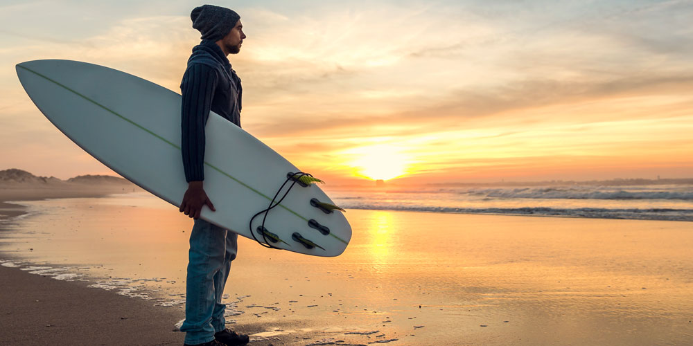 Homme avec sa planche de surf sur la plage
